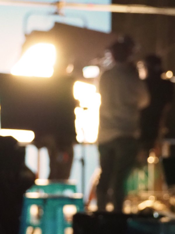 Production lights and crew behind the camera